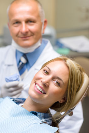 Woman smiling from her dental chair with her dentist next to her